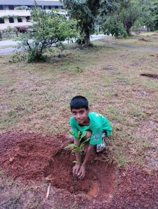 A kid planting a sapling to provide a clean environment to him